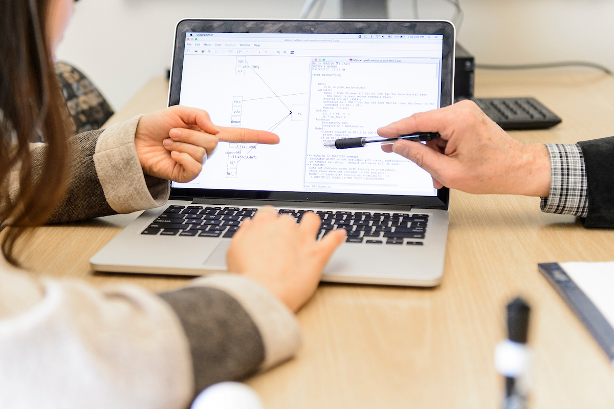 Laptop screen with two users pointing at items on the screen.
